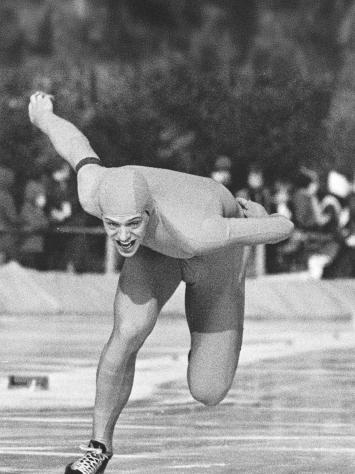 Een zwart-witfoto van een schaatser in een strak glad pak aan het schaatsen op de ijsbaan