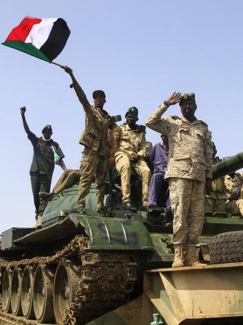 Vier mannen in legeruniform van het Sudanese regeringsleger staan op een tank en een zwaait met Sudanese vlag