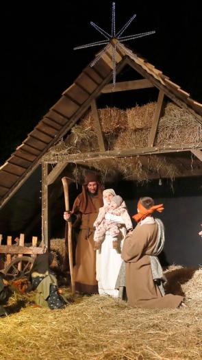 Een levende kerststal in de avond, met onder andere Maria, Jozef, Jezus en andere Bijbelse figuren eromheen