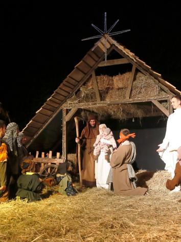 Een levende kerststal in de avond, met onder andere Maria, Jozef, Jezus en andere Bijbelse figuren eromheen