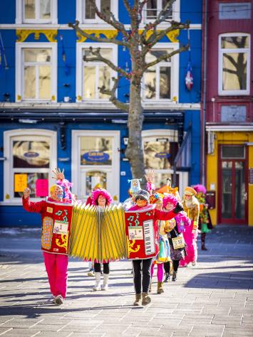Een groep mensen die aan het carnavallen is en muziek maakt. 