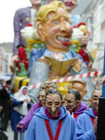 Een foto van een carnavalsoptocht met op de voorgrond mensen scherp in beeld die verkleed zijn.