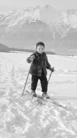 Een zwart-witfoto van een jong kind op ski's in de sneeuw in de bergen