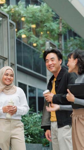 Een diverse groep mensen staat te kletsen buiten een kantoorpand.