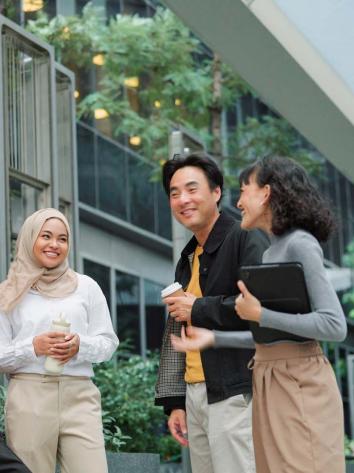 Een diverse groep mensen staat te kletsen buiten een kantoorpand.