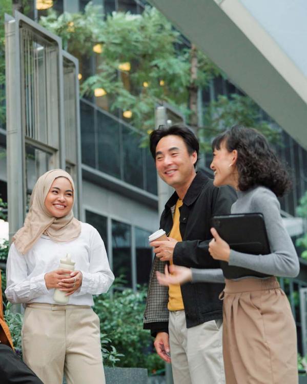 Een diverse groep mensen staat te kletsen buiten een kantoorpand.