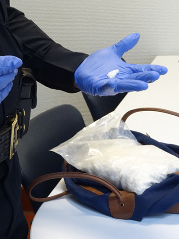 Politie-agent doorzoekt tas waarin de designerdrug Flakka is gevonden.