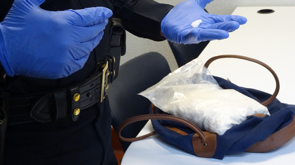 Politie-agent doorzoekt tas waarin de designerdrug Flakka is gevonden.