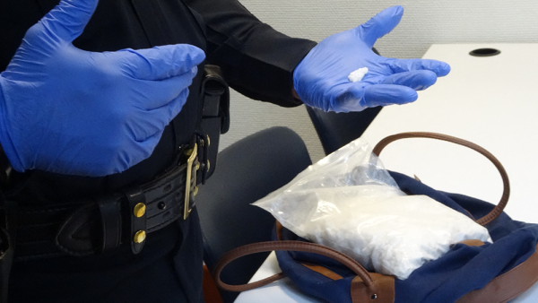 Politie-agent doorzoekt tas waarin de designerdrug Flakka is gevonden.