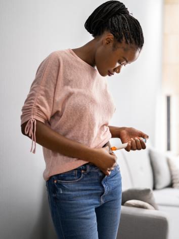 Een vrouw injecteert zichzelf met een spuit in haar buik voor haar ivf-behandeling 