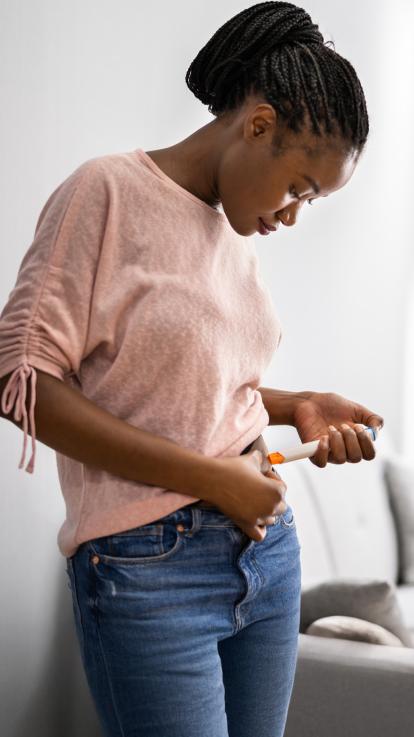 Een vrouw injecteert zichzelf met een spuit in haar buik voor haar ivf-behandeling 