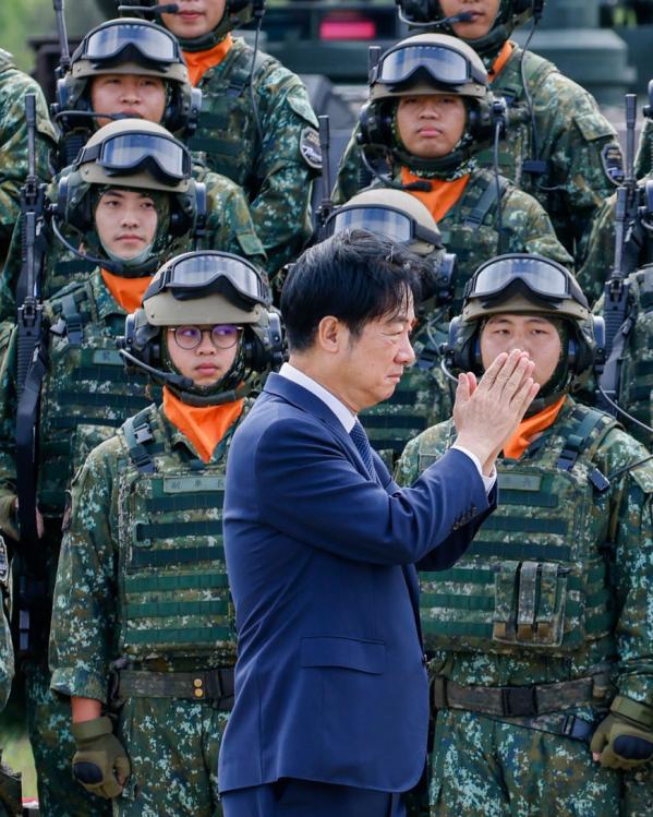 Een foto van de Taiwanese president die met zijn handen plat tegen elkaar gedrukt langs Taiwanese militairen in uniform loopt
