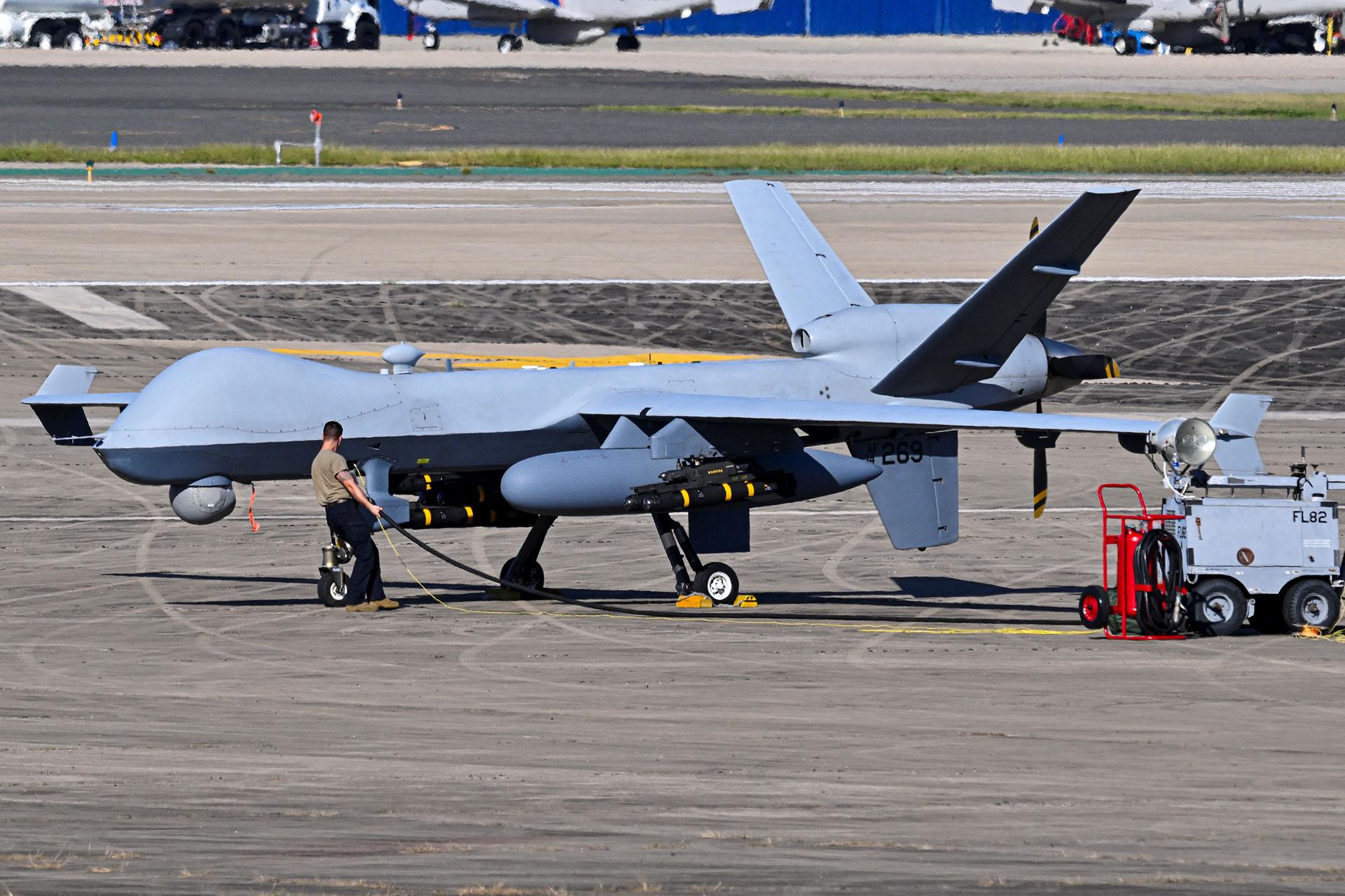 Een man tankt een enorme drone bij op een vliegveld.