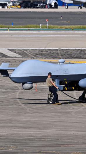 Een man tankt een enorme drone bij op een vliegveld.