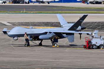 Een man tankt een enorme drone bij op een vliegveld.