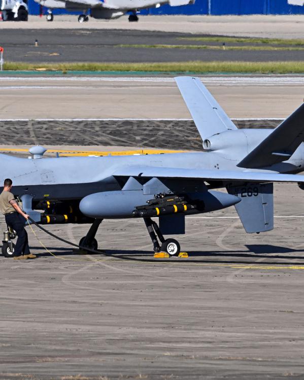 Een man tankt een enorme drone bij op een vliegveld.