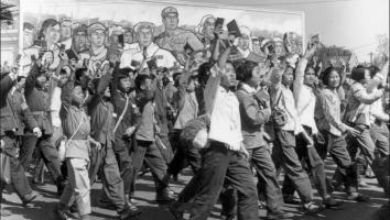 Een zwart-witfoto van Rode Gardisten, grotendeels studenten, die zwaaien met het Rode Boekje van Mao terwijl ze een parade in de straten van Peking lopen