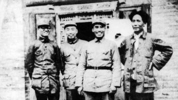 Een onscherpe, oude zwart-witfoto van vier partijleiders van de Chinese communistische partij, die lachend poseren voor de camera.