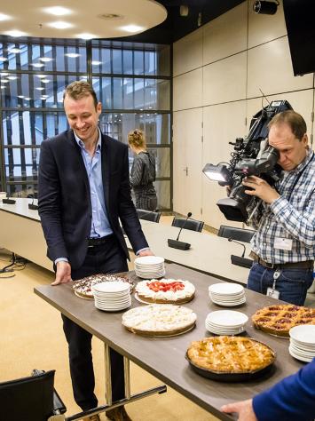 Een tafel vol vlaai wordt de gemeenteraadszaal van Den Haag in getild. 