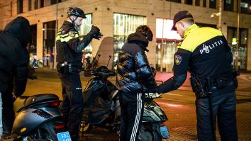 Twee agenten controleren jongens met scooters en bekijken legitimatiebewijs met een zaklamp.