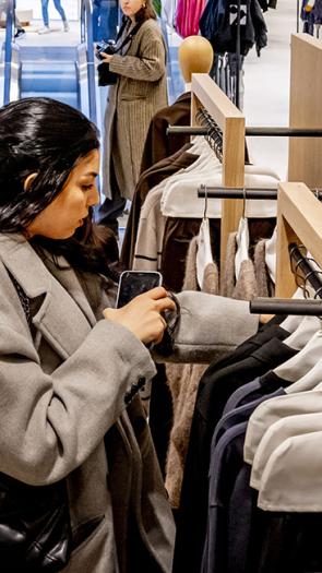 Vrouw zoekt in kledingrek in een winkel van de ZARA 