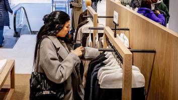Vrouw zoekt in kledingrek in een winkel van de ZARA