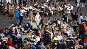 Een plein met meerdere hele volle terrassen. Het is zonnig en mensen zijn zomers gekleed