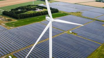 Luchtfoto van een windmolen met daarachter een weiland volgebouwd met zonnepanelen. 