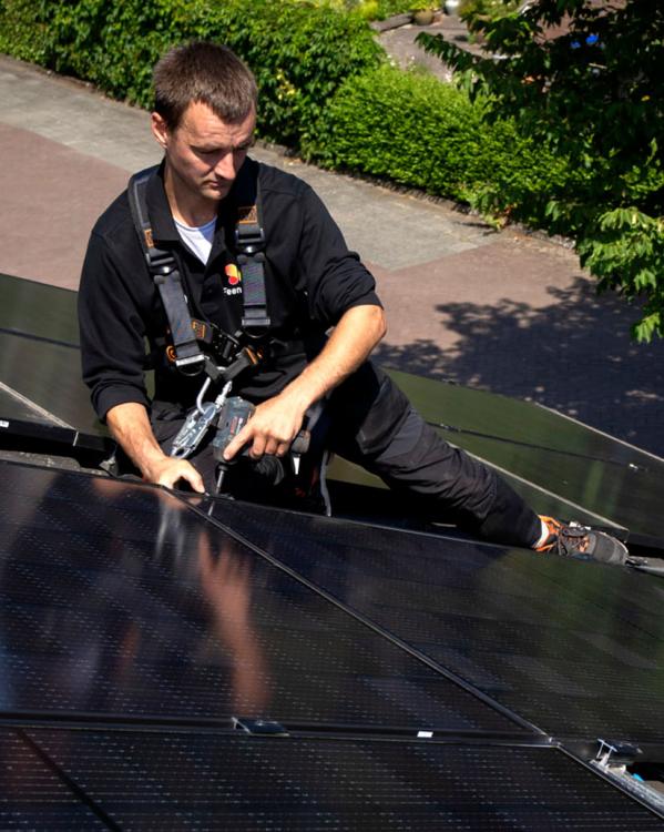 twee personen leggen zonnepanelen op het dak