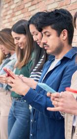 meerdere mensen op een rij die op hun eigen mobiele telefoon kijken