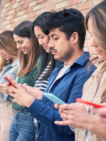 meerdere mensen op een rij die op hun eigen mobiele telefoon kijken