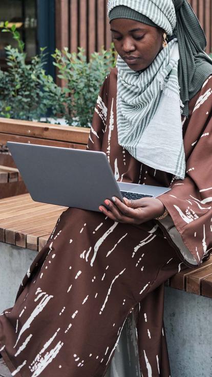 Een vrouw aan het werk op haar laptop op een bankje buiten
