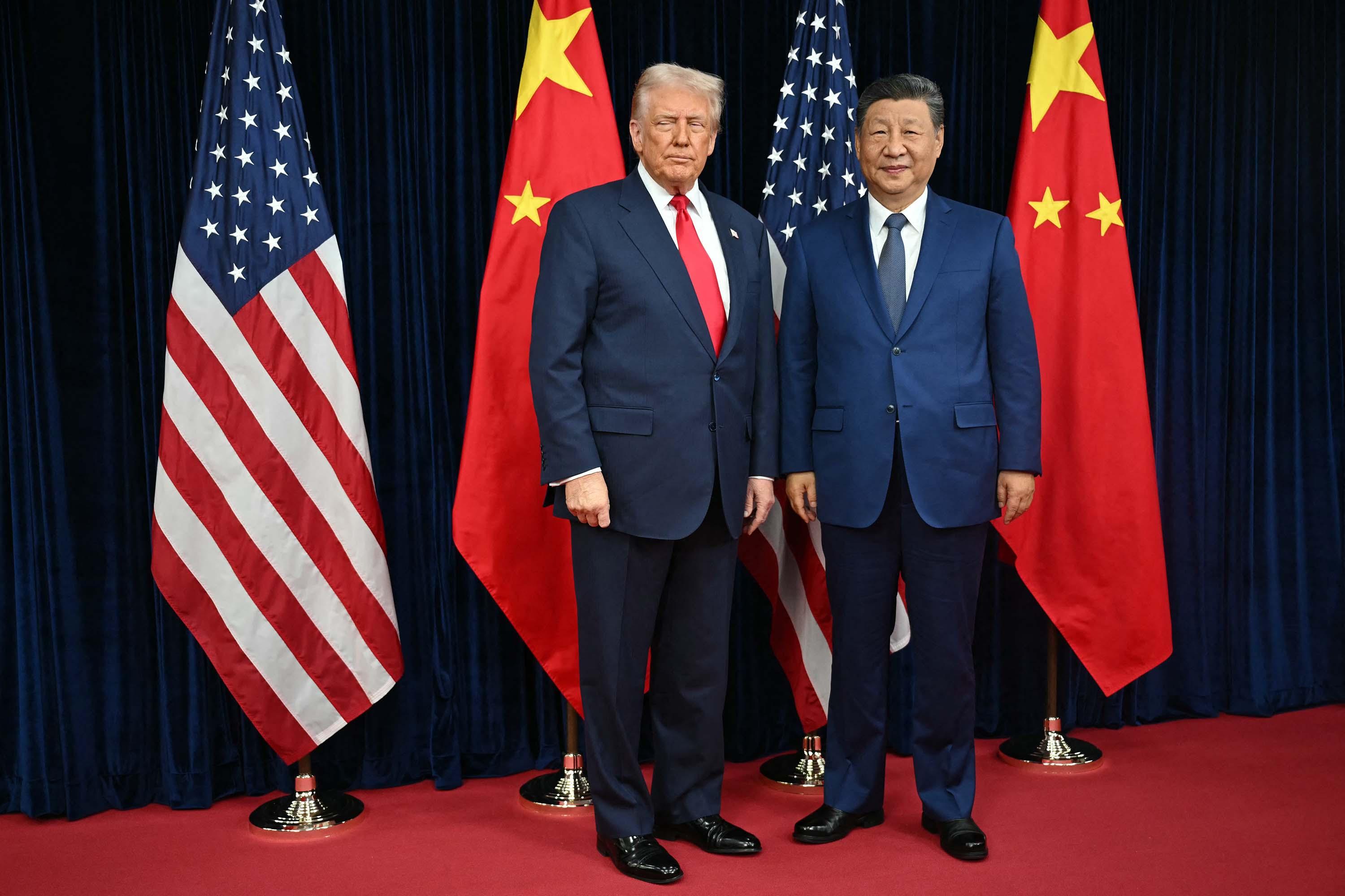 Amerikaanse president Donald Trump en Chinese president Xi Jinping poseren samen voor een foto met de Amerikaanse en Chinese vlaggen op de achtergrond.