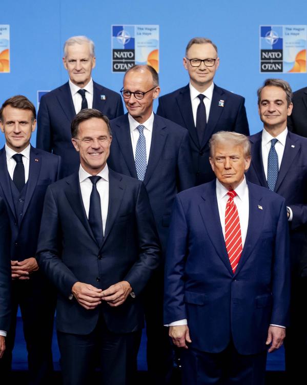 Wereldleiders in pak poseren voor een blauwe achtergrond op de NAVO top in 2025. Onder andere Mark Rutte, Donald Trump, Emmanuel Macron, Victor Órban en Friedrich Merz.