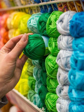 Een hand reikt naar een groen bolletje garen.