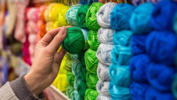 Een hand reikt naar een groen bolletje garen.