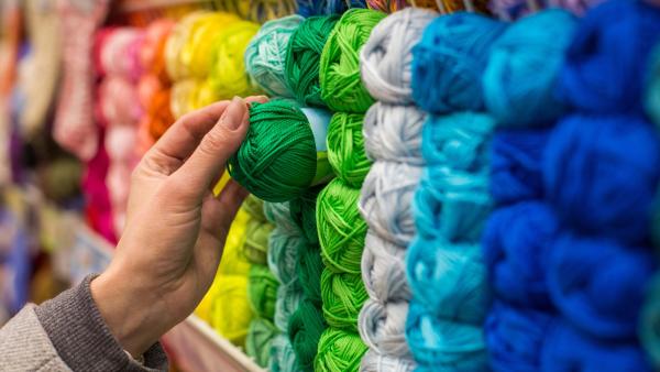 Een hand reikt naar een groen bolletje garen.