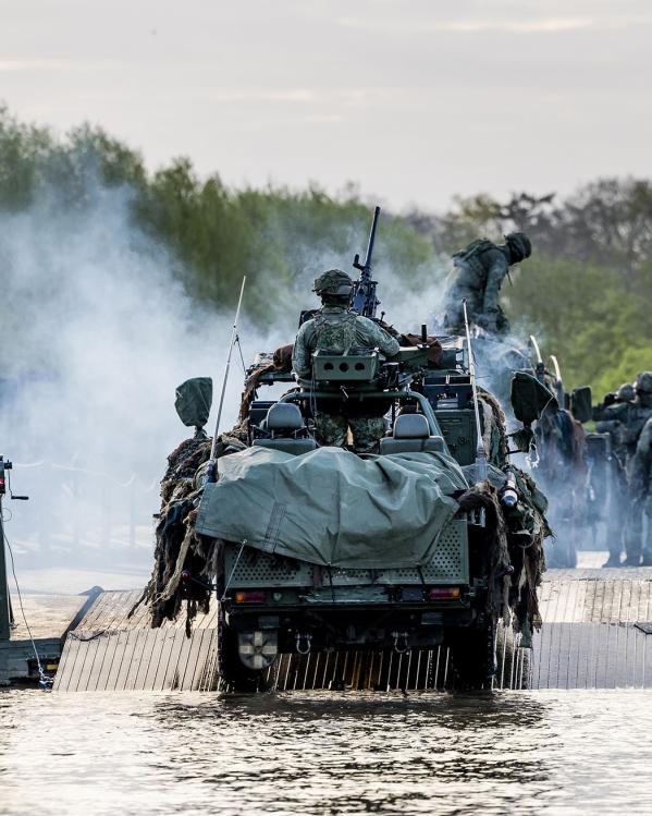 Een gepantserd voertuig steekt een rivier over.