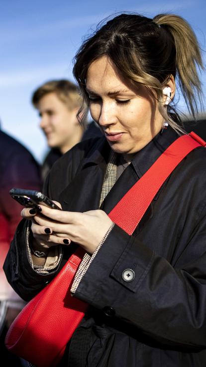 Vrouw loopt op straat maar kijkt naar smartphone