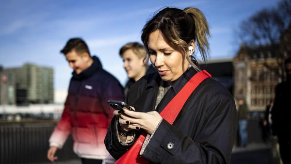 Vrouw loopt op straat maar kijkt naar smartphone