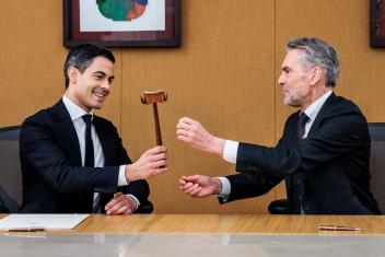 Oud-premier Dick Schoof draagt de symbolische hamer van het premierschap over aan Rob Jetten. Ze zitten samen aan een tafel.