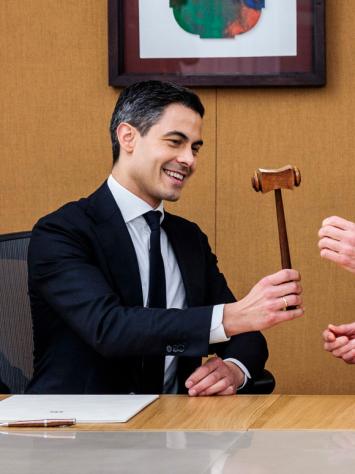Oud-premier Dick Schoof draagt de symbolische hamer van het premierschap over aan Rob Jetten. Ze zitten samen aan een tafel.