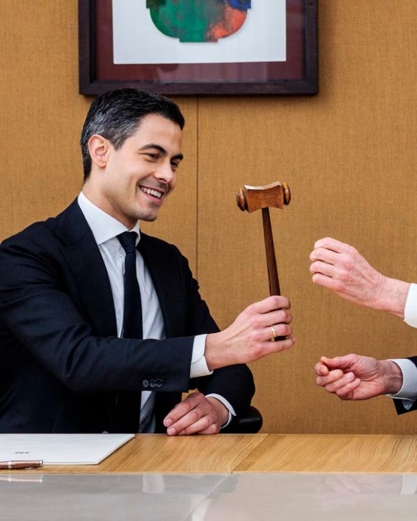 Oud-premier Dick Schoof draagt de symbolische hamer van het premierschap over aan Rob Jetten. Ze zitten samen aan een tafel.