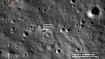 Een zwart-wit satellietbeeld van het maanoppervlak met veel kraters. In tekst staan er coördinaten bij van de Indiase maanlander.