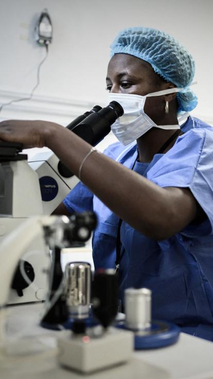 Een medewerker van een laboratorium werkt met een microscoop in een lab