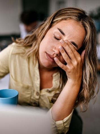 Vrouw wrijft over haar voorhoofd omdat ze overprikkeld is.
