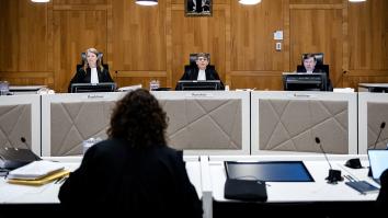 Meervoudige rechtszaal met 3 rechters tegenover een vrouw met krullen