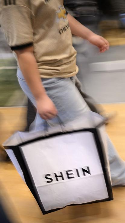 Een vrouw houdt een tas van fast fashion bedrijf Shein vast.