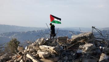 Een Palestijns kind staat met een Palestijnse vlag bovenop de resten van een Palestijns huis dat door Israëlische militairen is vernietigd.