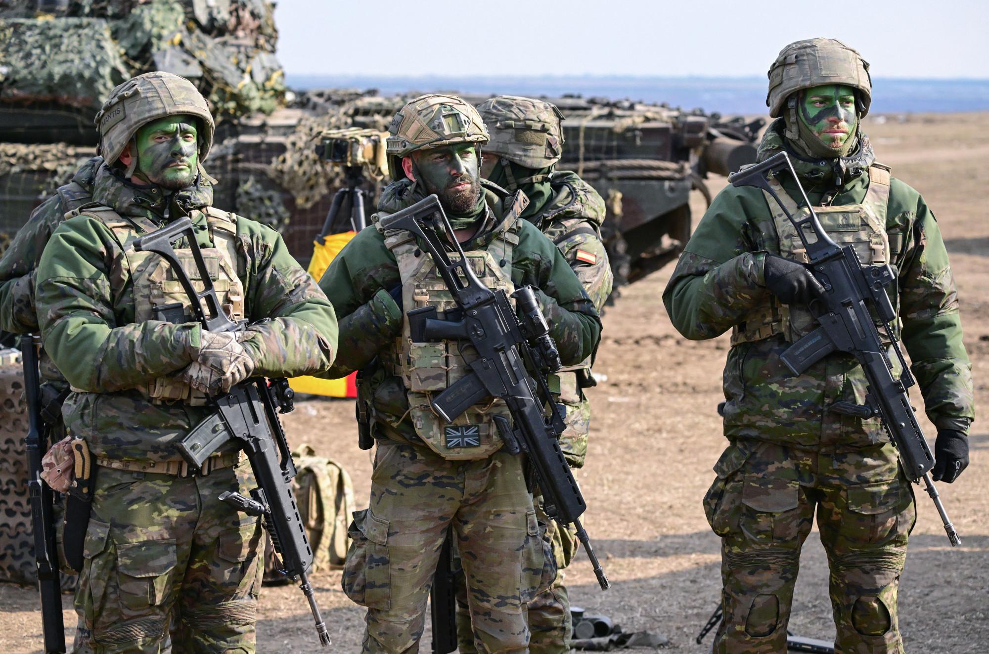 drie militairen staan in volledige uitrusting op een rij tijdens een gezamenlijke NAVO-oefening